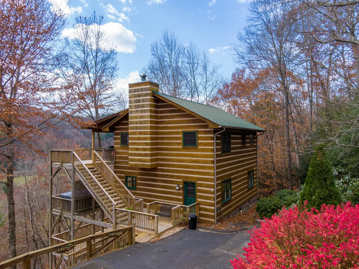 A cozy log cabin framed by a stairway leading up to the entrance and vibrant foliage in the foreground. The structure's rustic charm and the inviting outdoor space suggest a welcoming place for groups to gather and relax after a day outside.